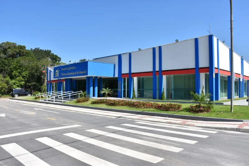 A foto é uma vista externa de um prédio governamental moderno em um dia ensolarado.